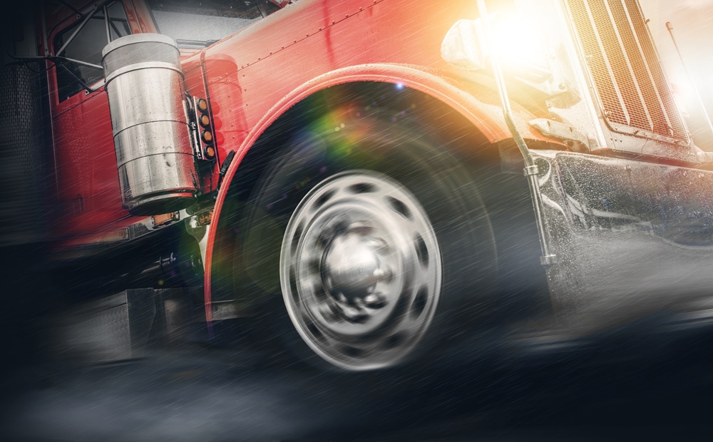 A semitruck driving in the rain.